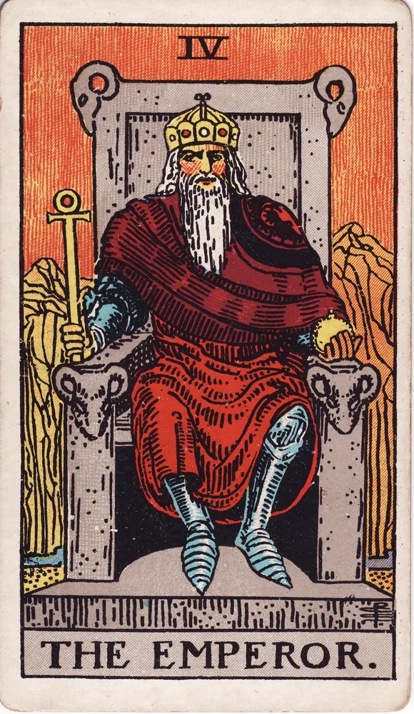 A bearded ruler in red robes on a stone throne carved with rams’ heads, holding a sceptre and an orb